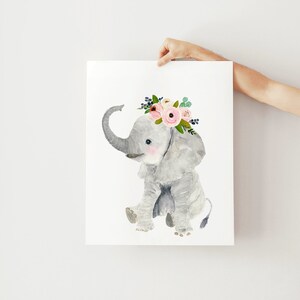 May include: A watercolor painting of a gray elephant wearing a pink and green floral crown. The elephant is sitting on its hind legs with its trunk raised.