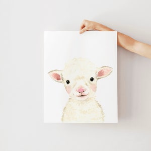 May include: A watercolor painting of a white lamb with pink ears and nose. The lamb is looking directly at the viewer with a sweet expression.