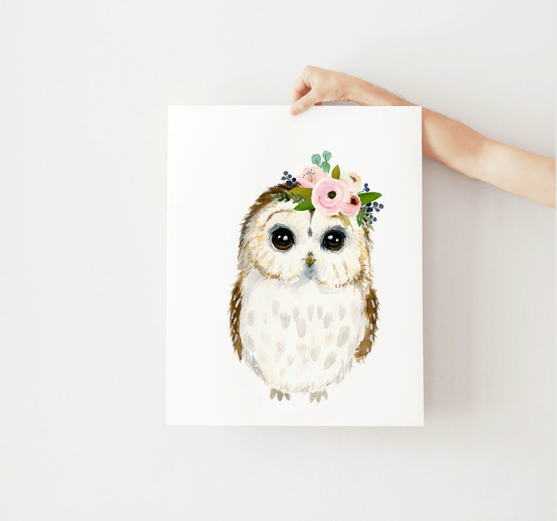 May include: A watercolor painting of an owl wearing a pink and white flower crown. The owl has brown and white feathers and large, dark eyes.