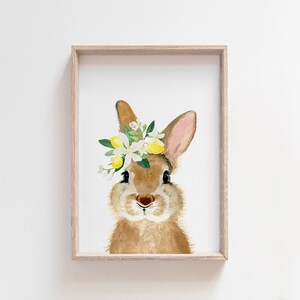 May include: A watercolor painting of a brown rabbit wearing a flower crown with white blossoms and yellow lemons. The rabbit is looking directly at the viewer.