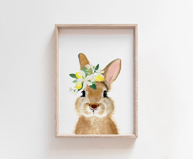 May include: A watercolor painting of a brown rabbit wearing a flower crown with white blossoms and yellow lemons. The rabbit is looking directly at the viewer.
