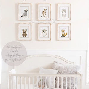 May include: Six framed watercolor illustrations of woodland animals with floral crowns, including a raccoon, deer, rabbit, bear, owl, and fox. The frames are white with a distressed finish and are hung on a white wall. The text "You are my sunshine" is written above the frames. The text "Pick your favorite animals and specify them in personalization box." is written below the frames.