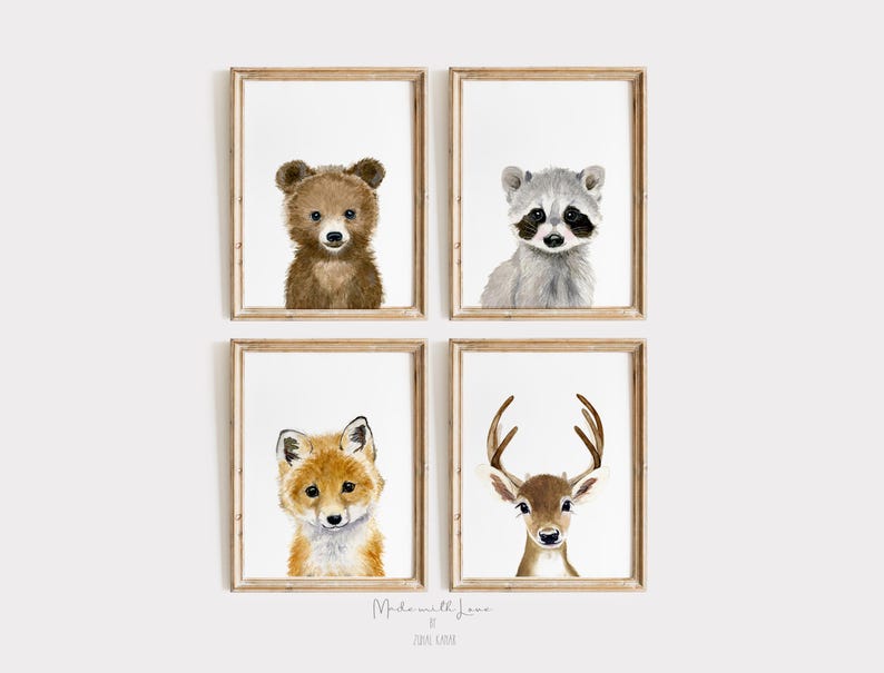 Op de afbeelding: Set van vier aquareldierprints met een bruine beer, een wasbeer, een vos en een hert. Elke print is ingelijst in een lichtbruin houten lijst.
