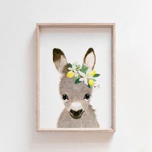 May include: A watercolor painting of a gray donkey wearing a flower crown with white flowers and yellow lemons. The donkey is looking directly at the viewer with a sweet expression.