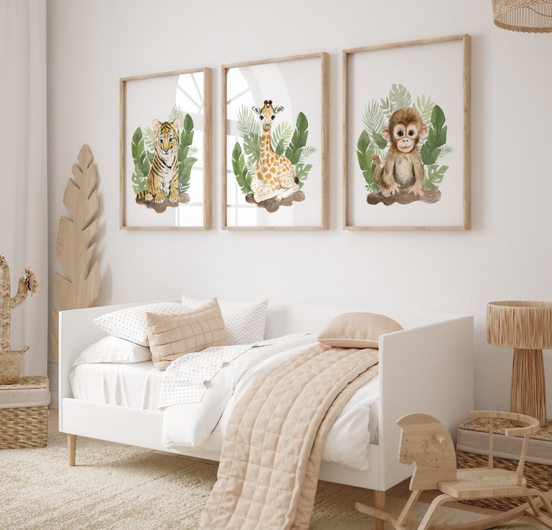 May include: Three framed watercolor illustrations of jungle animals. A tiger cub sits in green leaves, a giraffe calf stands in green leaves, and a monkey sits in green leaves.