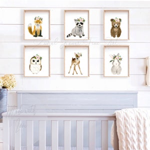 May include: A set of six watercolor animal prints featuring a fox, raccoon, bear, owl, deer, and rabbit. Each animal is wearing a floral crown and is set against a white background.