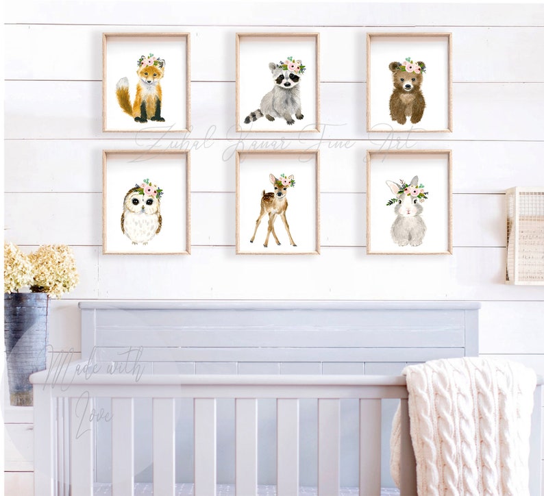 May include: A set of six watercolor animal prints featuring a fox, raccoon, bear, owl, deer, and rabbit. Each animal is wearing a floral crown and is set against a white background.