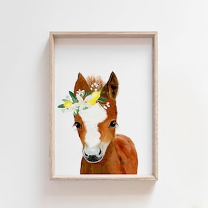 May include: A watercolor painting of a brown and white foal wearing a flower crown with yellow lemons. The foal is looking directly at the viewer.