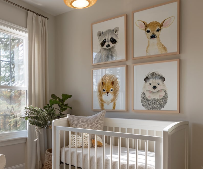 Op de afbeelding: Een wit wiegje met een wit matras en een wit dekentje. Er hangen vier ingelijste dierenprints aan de muur achter de wieg. De prints tonen een wasbeer, een hert, een egel en een eekhoorn.