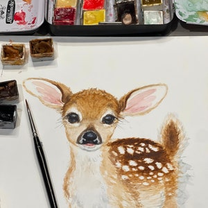 May include: Watercolor painting of a fawn with brown and white fur. The fawn has large, dark eyes and a pink nose. The painting is on a white background.