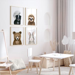 Op de afbeelding: Vier ingelijste dierillustraties in een witte kamer. De illustraties tonen een beer, een konijn, een luiaard en een stinkdier. De illustraties hangen aan een witte muur boven een witte tafel en stoelen.