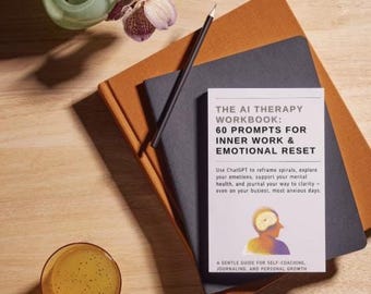 May include: A gray and orange book titled "The AI Therapy Workbook: 60 Prompts for Inner Work & Emotional Reset". The book cover features a graphic of a person's head with a brain inside. The text on the cover reads "Use ChatGPT to reframe spirals, explore your emotions, support your mental health, and journal your way to clarity - even on your busiest, most anxious days." The book is sitting on top of a brown and black notebook.
