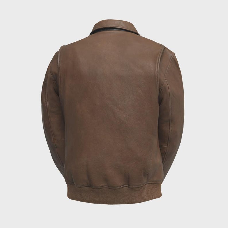 May include: A brown leather jacket with a bomber-style design. The jacket features a collar, ribbed cuffs, and a ribbed hem. The back view showcases the jacket's texture and stitching details. A classic outerwear piece.