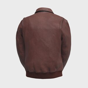 May include: A brown leather bomber jacket with a ribbed hem and cuffs. The jacket has a classic collar and a smooth, matte finish. The back view showcases the jacket's tailored fit and design.