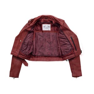 Puede incluir: Chaqueta de cuero burdeos, abierta para revelar el forro interior. La chaqueta presenta un estilo motero cl&aacute;sico con cuello de solapa, cremallera asim&eacute;trica y m&uacute;ltiples bolsillos. El interior es de un tono burdeos m&aacute;s oscuro.