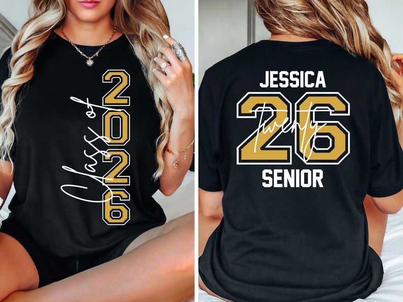 Puede incluir: Camiseta negra con letras doradas y blancas. La parte delantera muestra "Class of 2026" y la trasera dice "Jessica 26 Senior". Los n&uacute;meros est&aacute;n delineados en dorado con un borde blanco, y el nombre est&aacute; en escritura blanca.