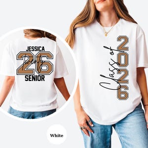 Puede incluir: Camiseta blanca con "Class of 2026" en letras marrones y negras en la parte delantera. La parte trasera de la camiseta presenta el nombre "Jessica", el n&uacute;mero "26" y la palabra "SENIOR" en una combinaci&oacute;n de colores similar.