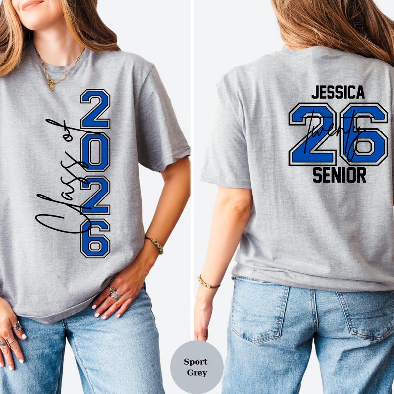 Puede incluir: Camiseta gris deportiva con texto azul y blanco. La parte delantera de la camiseta dice "Class of 2026" en fuente de escritura y letras de bloque. La parte trasera de la camiseta dice "Jessica 26 Senior" con una firma.