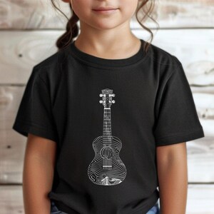 May include: Black t-shirt featuring a white line drawing of a ukulele. The ukulele design has a detailed, wave-like pattern on the body. The word "Black" is in a black circle in the upper left corner.