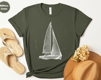 Peut inclure: T-shirt vert militaire avec un dessin au trait blanc d'un voilier. Le t-shirt a des manches retroussées et un nœud en bas. Des sandales tissées et un chapeau beige sont également visibles.