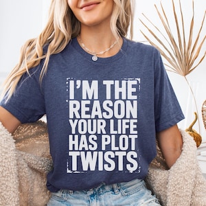 May include: Heather navy t-shirt with the text "I'M THE REASON YOUR LIFE HAS PLOT TWISTS" in a white, distressed font. The shirt is a crew neck and is made of a soft material. The shirt is a casual wear item.
