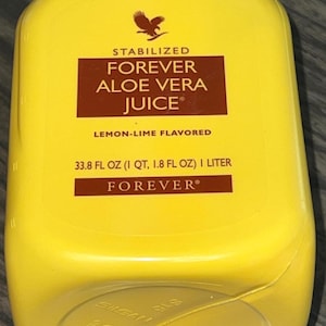 May include: Yellow bottle of Forever Aloe Vera Juice, lemon-lime flavored. The label is brown with white text and includes the brand name, product name, and volume: 33.8 fl oz (1 qt, 1.8 fl oz) 1 liter.
