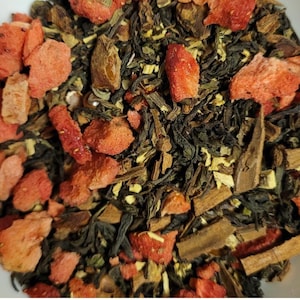 May include: A black tea blend in a clear-windowed pouch, labeled "Paisley Sweets." The blend includes freeze-dried strawberry pieces, licorice root, star anise, and cinnamon sticks. The image also shows a close-up of the tea and wrapped candies.