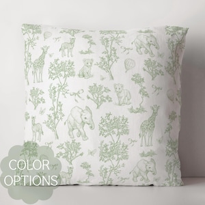 May include: A white pillowcase with a green safari animal print. The print features elephants, giraffes, lions, and zebras. The pillowcase is perfect for a nursery or child's room.
