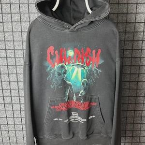 May include: Dark gray hoodie with a front pocket and a hood. The front graphic features the word "CHILDISH" in red, with an alien and UFO design. Text at the bottom reads "COULD IT BE TOO LATE ALIENS CAME FROM OUTER SPACE & STOLE OUR CHILDHOOD".