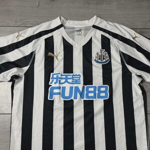 Puede incluir: Camiseta de f&uacute;tbol a rayas blancas y negras con cuello en V. Presenta el escudo del Newcastle United, el logotipo de Puma y el logotipo del patrocinador Fun88 en azul. La camiseta est&aacute; hecha de un material ligero.