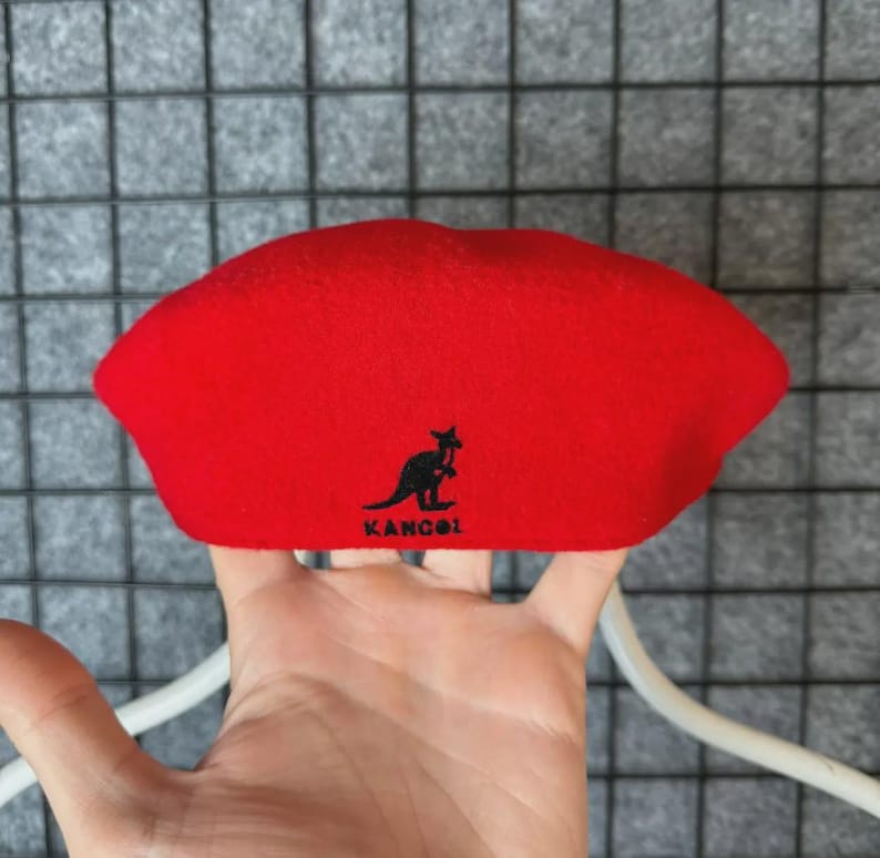 Puede incluir: Un boina roja brillante con el logotipo de Kangol, que presenta un canguro negro. La boina est&aacute; hecha de un material suave y es de estilo cl&aacute;sico. El sombrero es de color liso y es un accesorio de moda popular.