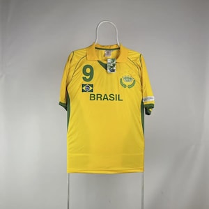 May include: A yellow Brazil soccer jersey with green accents. The jersey features the number 9, the word "BRASIL", and a green and yellow emblem. The shirt is hanging on a white hanger.