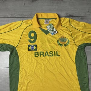 May include: A yellow and green Brazil soccer jersey with the number 9 on the front. The word "BRASIL" is printed across the chest. The jersey has a collar and green accents on the sleeves and sides. A tag is attached.