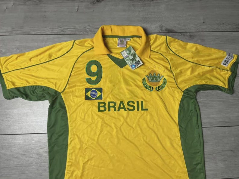 May include: A yellow and green Brazil soccer jersey with the number 9 on the front. The word "BRASIL" is printed across the chest. The jersey has a collar and green accents on the sleeves and sides. A tag is attached.