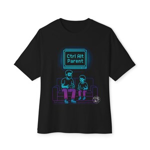 May include: Black t-shirt featuring a neon-style graphic of a parent and child playing video games on a couch. Above them is a screen with the text "Ctrl Alt Parent". The design uses shades of blue, purple, and white.