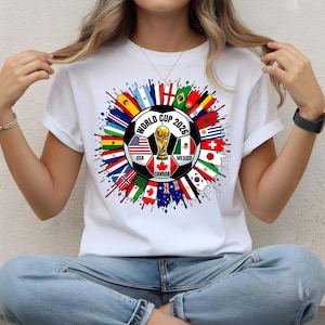 May include: A white ceramic mug with a black handle and the text "But First, Coffee" in a black, handwritten-style font. The mug is on a white surface.