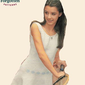 May include: A white knitted tennis dress with a flared skirt and blue floral accents. The dress is sleeveless and has a scoop neckline. The image includes the text "Knot Forgotten PATTERNS". A tennis racket is also visible.