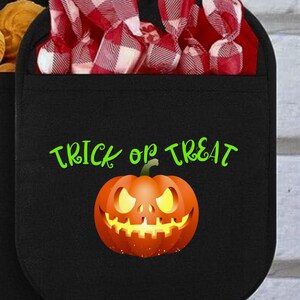 May include: A black oven mitt with a pocket containing red and white checkered wrapped candies. The front features the green text "TRICK OR TREAT" above an orange glowing jack-o'-lantern pumpkin with a sinister expression and yellow eyes.
