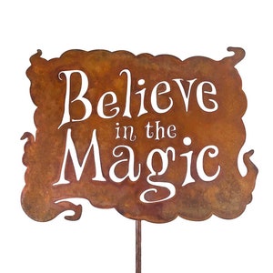 Puede incluir: Un letrero de metal rústico con un acabado marrón y desgastado. El letrero tiene forma de nube y presenta el texto "Believe in the Magic" en letras blancas.