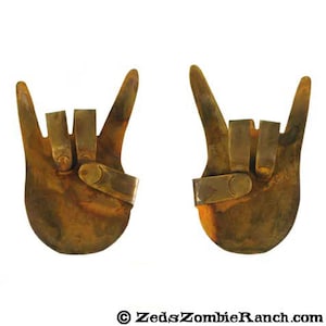 Puede incluir: Dos manos de metal oxidado haciendo el gesto de rock and roll. Las manos están levantadas en el aire y están hechas de un metal rugoso y texturizado.