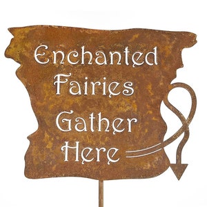 May include: Rustic metal sign with a whimsical design. The sign is rusty brown and features a white inscription that reads "Enchanted Fairies Gather Here".