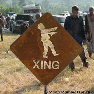 May include: A rusty brown road sign with a white silhouette of a zombie walking and the word "XING" written in white letters.