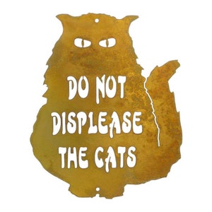 以下が含まれることがあります： 「DO NOT DISPLEASE THE CATS」の文字が切り抜かれた、猫の形をした錆びた金属製のサイン。サインは、金茶色の仕上がりで、猫の目の形をした切り抜きがあります。