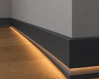 May include: A matte black baseboard molding installed along a corner where two walls meet. The baseboard features an integrated linear LED light strip that casts a warm, golden glow downward onto the light brown wood grain flooring.