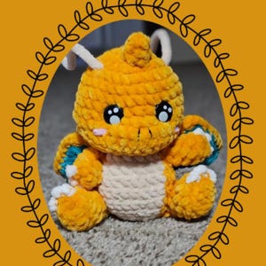 Op de afbeelding: Een gehaakte Dragonite-knuffel uit de "Chibi Series" met oranje, crème en blauwe accenten. De knuffel heeft grote zwarte ogen en witte antennes. De afbeelding bevat de tekst "Eevelutionary Crochet" en "Dragonite".