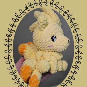 May include: A yellow and orange crocheted plush toy featuring a fox-like creature with multiple tails, black plastic eyes, and pink stitched cheeks. The text Chibi Series: Ninetalels is displayed at the top, with Eevelutionary Crochet branding.