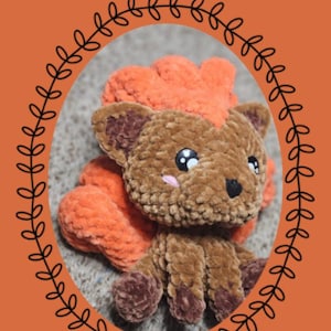 Könnte beinhalten: Gehäkeltes Vulpix-Plüschtier aus der "Chibi-Serie" mit braunem und orangefarbenem Garn. Das Plüschtier hat große, ausdrucksstarke Augen und einen flauschigen Schwanz. Der Text "Eevelutionary Crochet" und "Vulpix" ist im Bild enthalten.