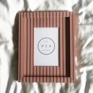 Marco de fotos a rayas naranjas y burdeos, envuelto a mano: una llamativa decoración para la pared.