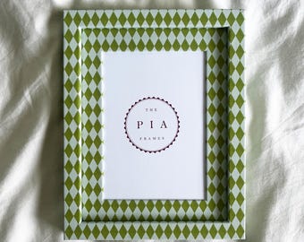 May include: A rectangular picture frame with a green and white diamond pattern. The frame has a white interior with the text "THE PIA FRAMES" in a circular design.