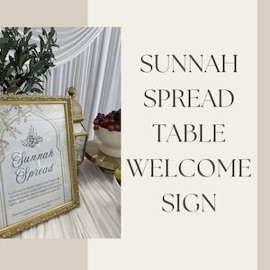 May include: A rectangular gold-toned frame containing a white sign with black text that reads Sunnah Spread, along with Arabic calligraphy. The sign includes a decorative arch border and is displayed on a white draped surface next to a gold lantern.